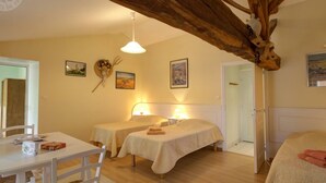 Een gezellige kamer met twee bedden, een eettafel en een houten balk.