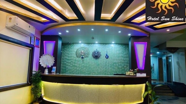 A reception desk with a green textured wall, decorative wall art, and purple lighting accents. - HOTEL SUNSHINE (Baharampur)