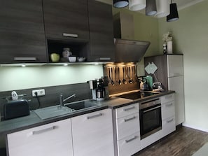 A modern kitchen with a stainless steel sink, a built-in oven, and a coffee maker.