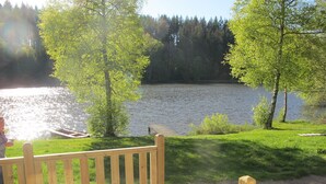 Een houten terras met uitzicht op een meer en bos.