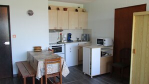 A compact kitchen with a dining table, chairs, a microwave, a toaster, and a coffee maker.