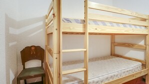 A bunk bed with a wooden frame and a mattress with a patterned cover.