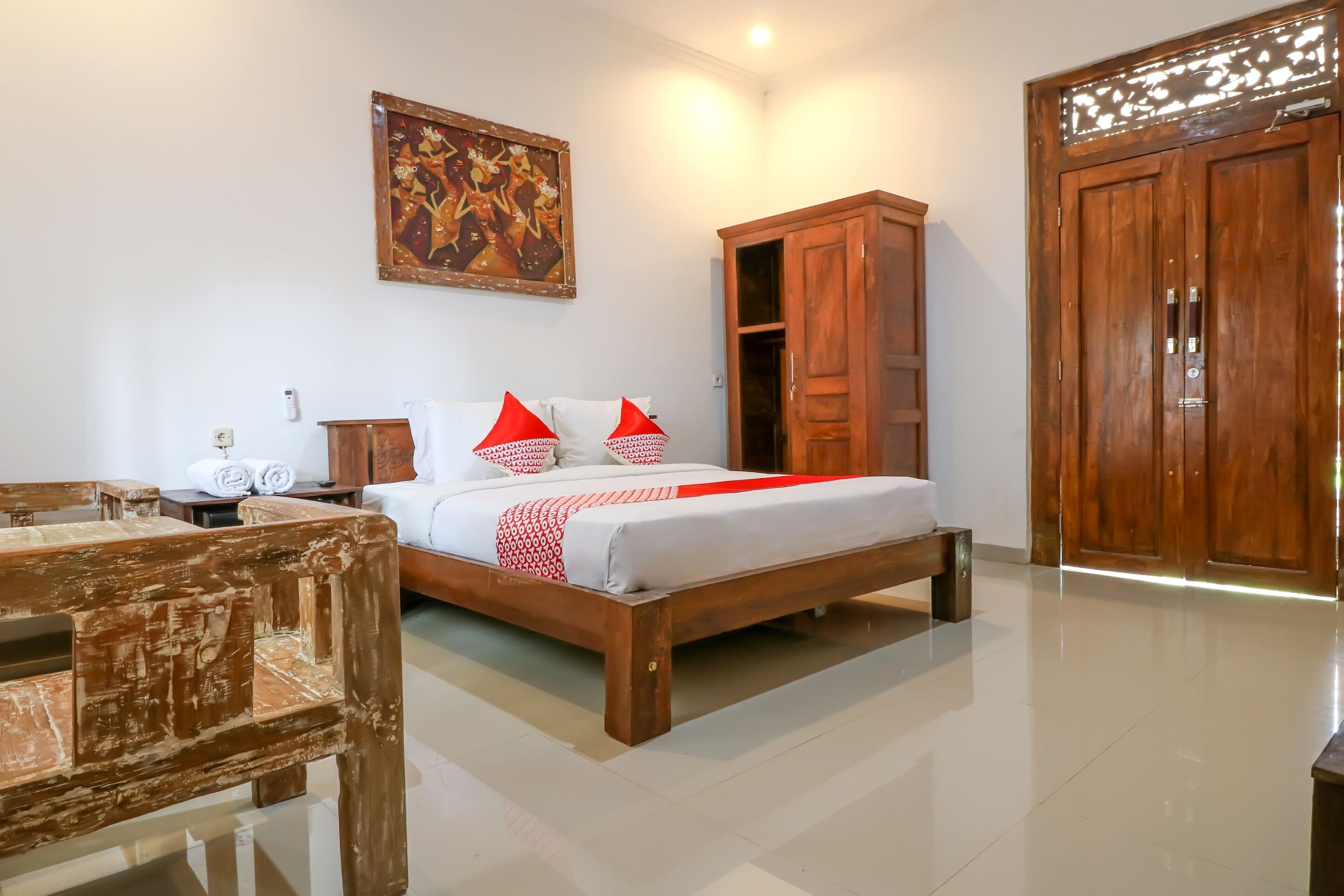 A bedroom with a bed, wooden wardrobe, and a painting on the wall.