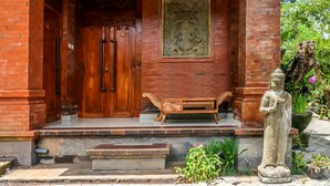 Une entrée d’immeuble avec une porte en bois, un banc et une statue.