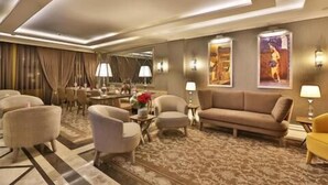 A spacious hotel lobby with a large sofa, armchairs, a dining area, and artwork on the walls. - Basilica GuestHouse (Istanbul)