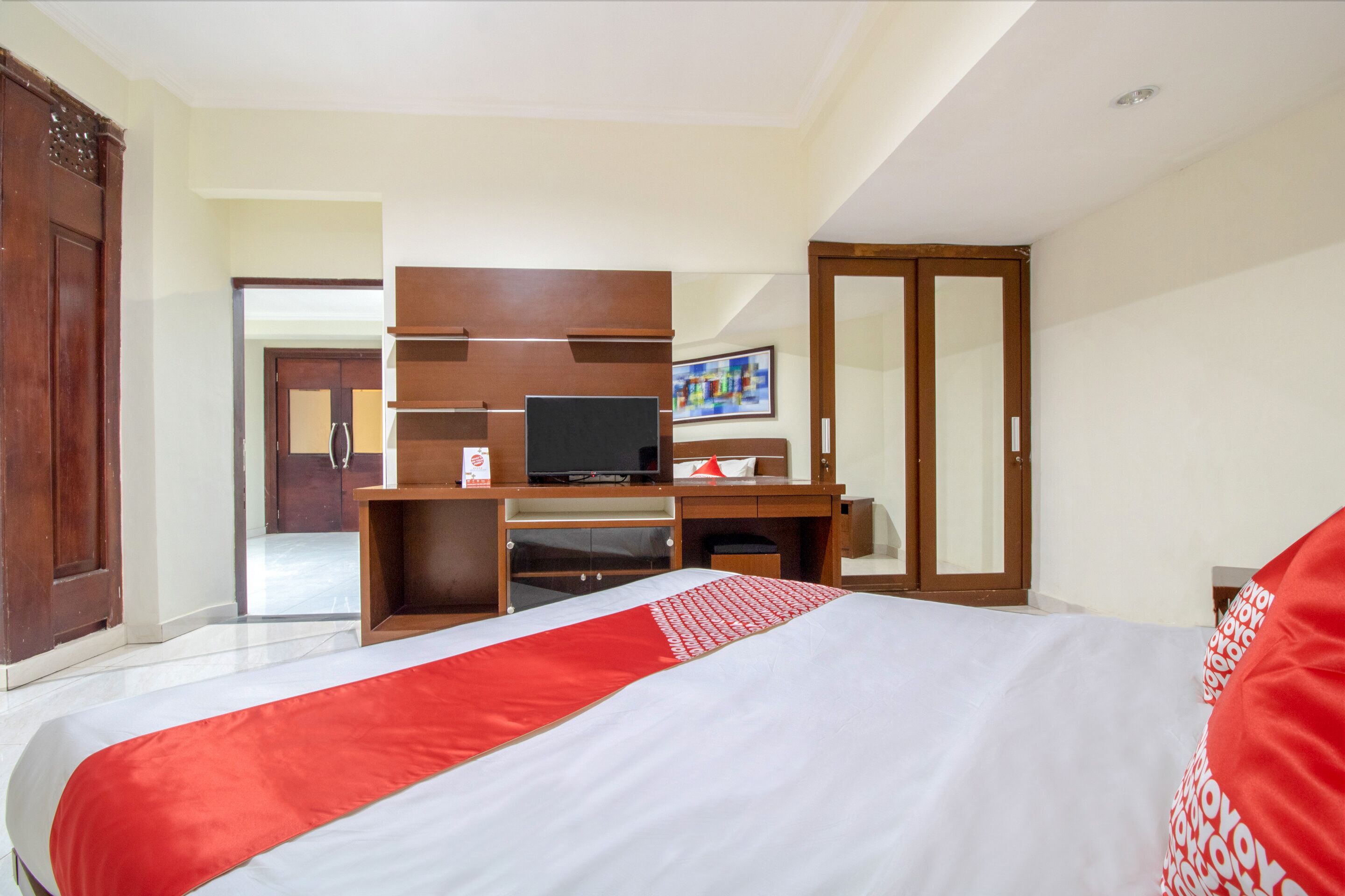 A hotel room with a large bed, a desk with a computer, a wardrobe, and a television.
