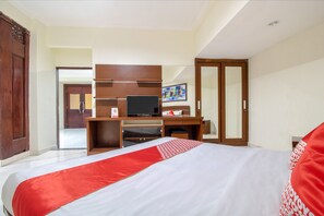 A hotel room with a large bed, a desk with a computer, a wardrobe, and a television. - Flagship 2688 Guntur Hotel (Denpasar)