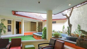 Un hall d’hôtel doté d’un espace salon central, d’un petit jardin et d’une vue sur la rue.