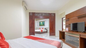 Une chambre d’hôtel avec un lit, une télévision, une armoire en bois et un tableau au mur.