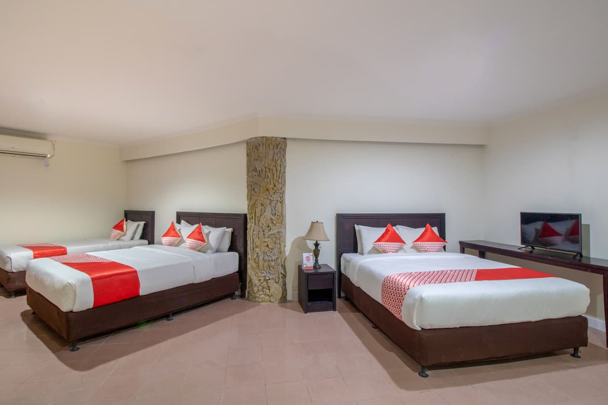 Une chambre d’hôtel avec deux lits, une télévision et une petite table avec une lampe.