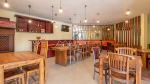 L’intérieur d’un restaurant, avec des meubles en bois, des luminaires suspendus et un panneau sur lequel on peut lire : « Restez humble ».
