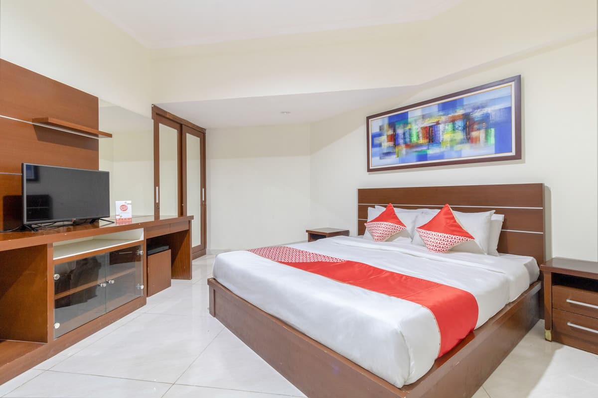 Une chambre d’hôtel avec un lit, une télévision, un bureau et un tableau au mur.