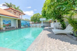 A swimming pool with clear water, surrounded by lounge chairs and a mural on the building. - Flagship 2688 Guntur Hotel (Denpasar)