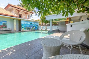 A swimming pool with a mural, wicker furniture, and a bar area. - Flagship 2688 Guntur Hotel (Denpasar)