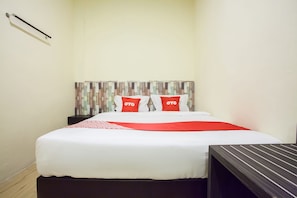 A neatly made bed with white and red bedding, a striped table beside it, and a wooden headboard. - OYO 2361 Hotel Winston (Medan)