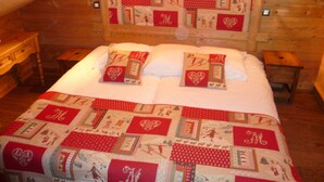 A cozy bedroom with a wooden headboard featuring a quilted design, a neatly made bed with matching pillows, and a small wooden nightstand on each side.