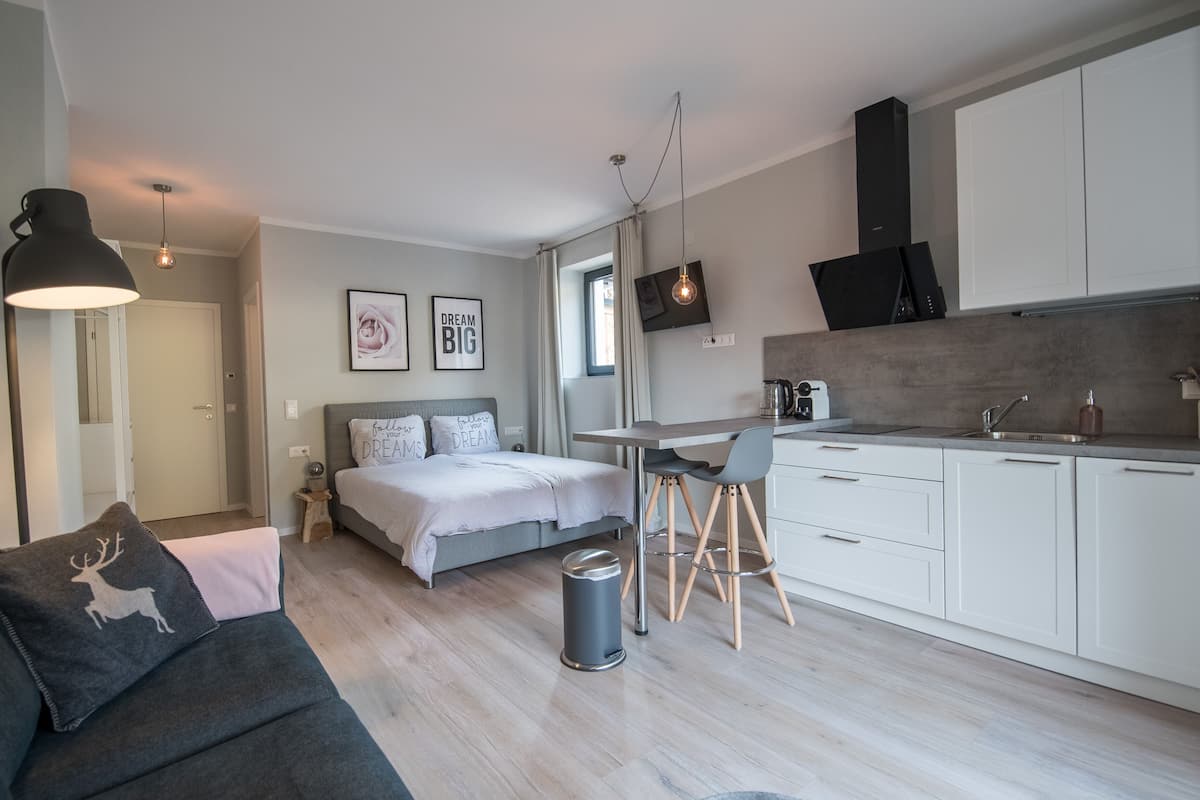Um espaço de estar moderno e compacto, com cama, sofá, área de refeições e cozinha compacta.