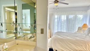 A bedroom with a large bed, a ceiling fan, and a view of the outdoors through sheer curtains. - Weekly / Monthly Rental - Spacious Condo IN Longboat Key Resort Close TO Pool, Tennis And Beach! (Longboat Key)