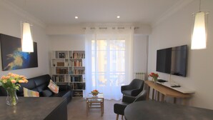 A modern living room with a sofa, coffee table, bookshelf, and a TV. - Libération (Nice)