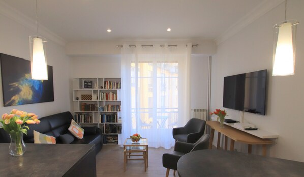 Un salon moderne comprenant un canapé, une table basse, une bibliothèque et un téléviseur.