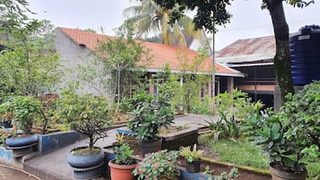 A garden with various potted plants and a brick building with a tiled roof.