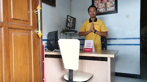 A reception desk with a computer monitor, a chair, and a QR code sign. - OYO 2302 Blue House Costel Syariah (Cianjur)