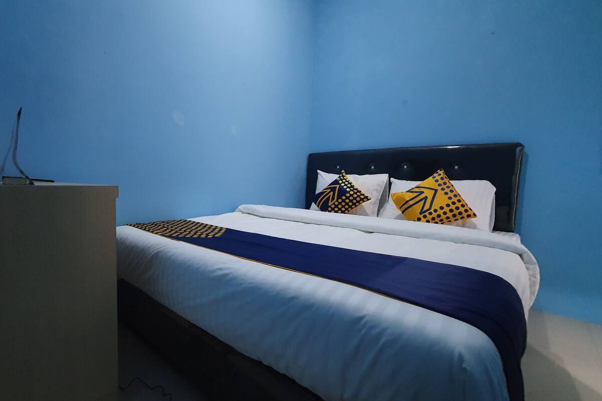 Una habitación de hotel con una cama, cabecera y escritorio.
