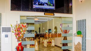 A hotel entrance with a restaurant sign, a decorative vase, and a wall-mounted television. - Peace Hotel and Suites (Ilorin)