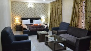 A hotel room with a bed, two nightstands, a glass coffee table, two armchairs, and a sofa. - Peace Hotel and Suites (Ilorin)