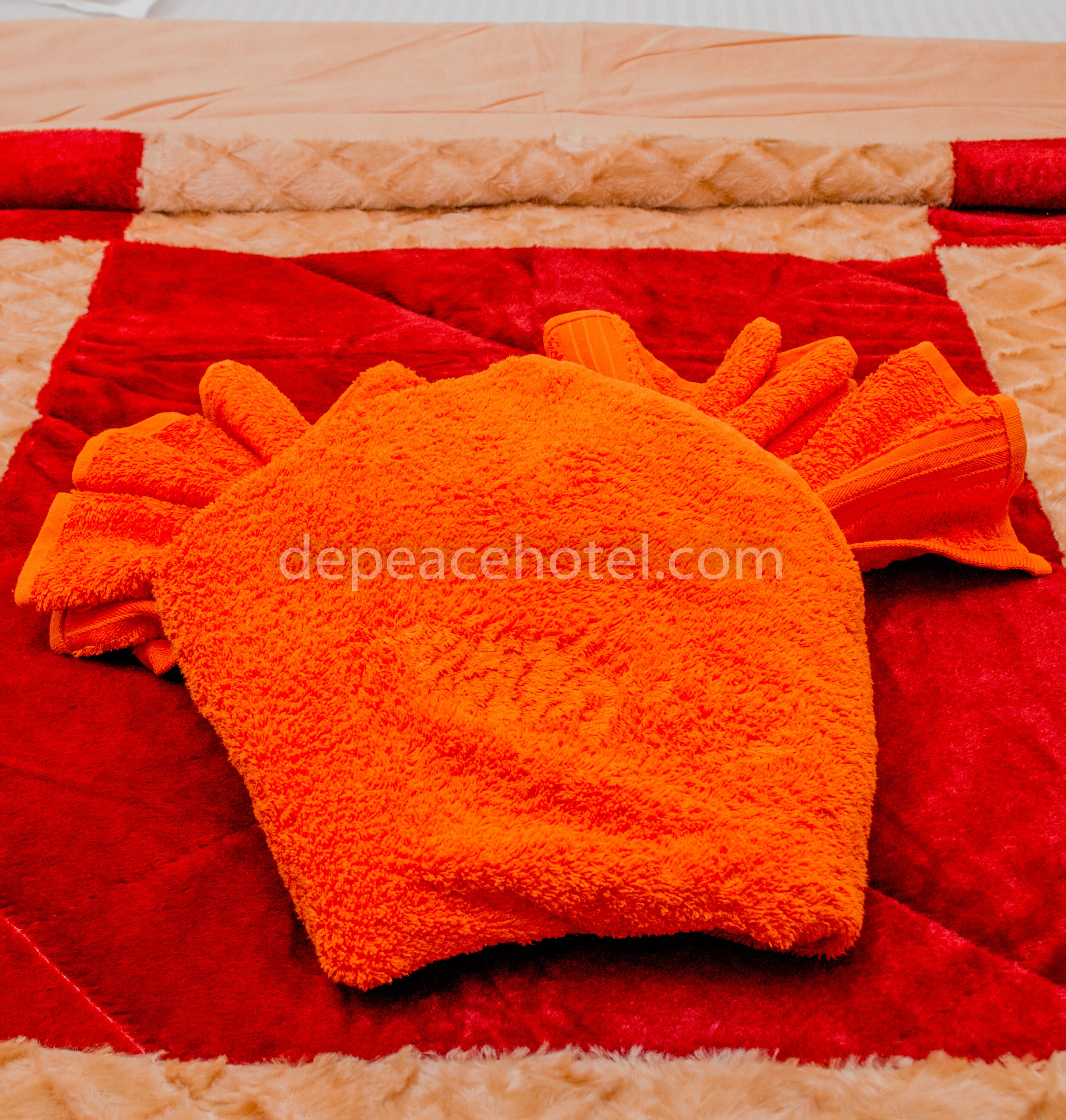 A plush orange towel with a unique design, placed on a red and beige textured rug.