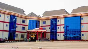 A multi-story hotel with a central entrance, large windows, and a red and white color scheme. - Peace Hotel and Suites (Ilorin)