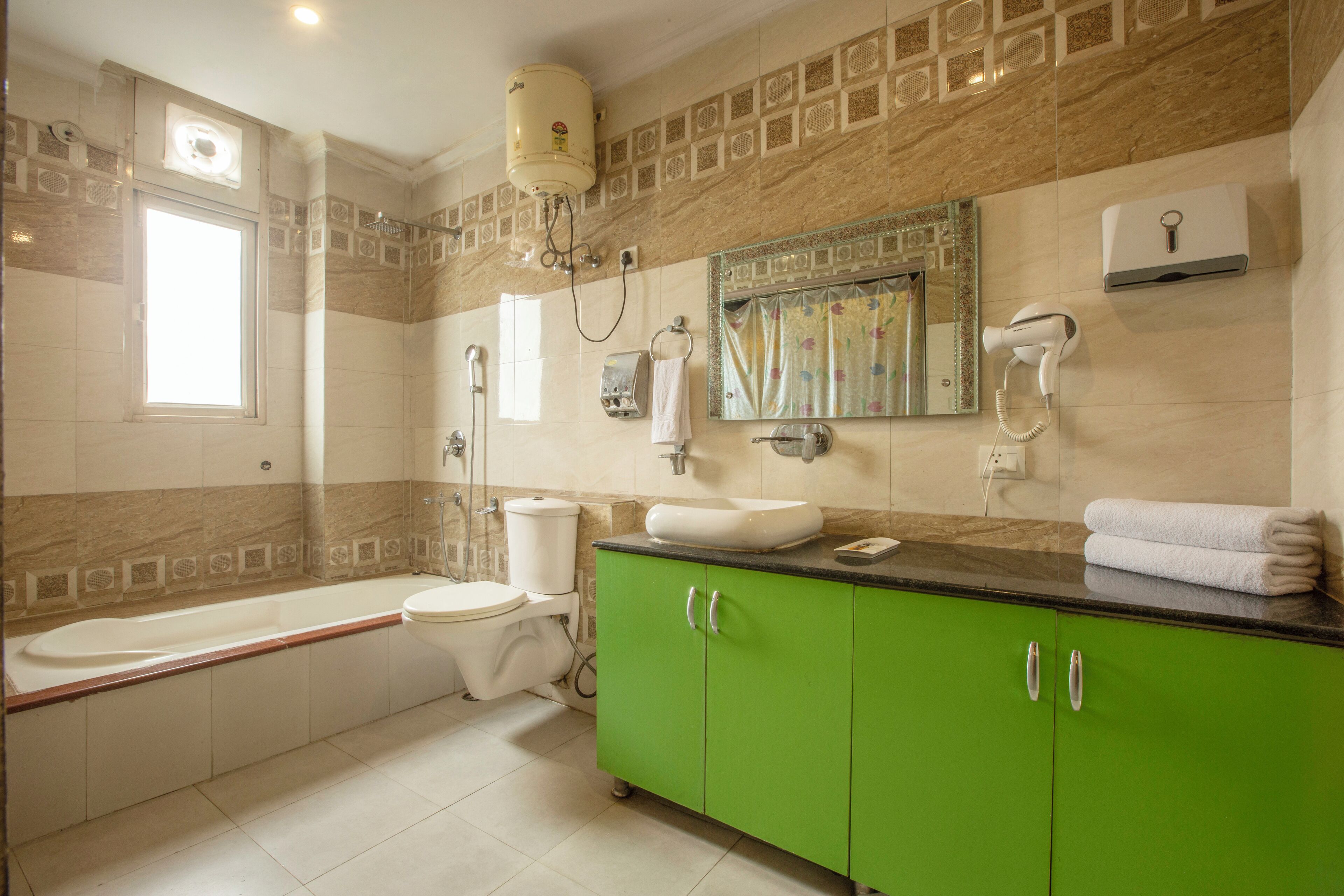 A bathroom with a bathtub, toilet, green cabinets, a sink, and a mirror.