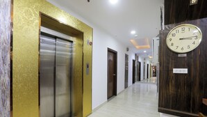 Un pasillo de hotel con ascensores, un reloj y un cartel que indica que la ubicación es Tokio.