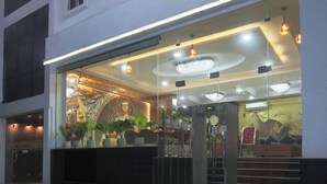A hotel entrance with a glass facade, a Buddha statue, and a clock. - Castle Blue By Excellent Hospitality (New Delhi)
