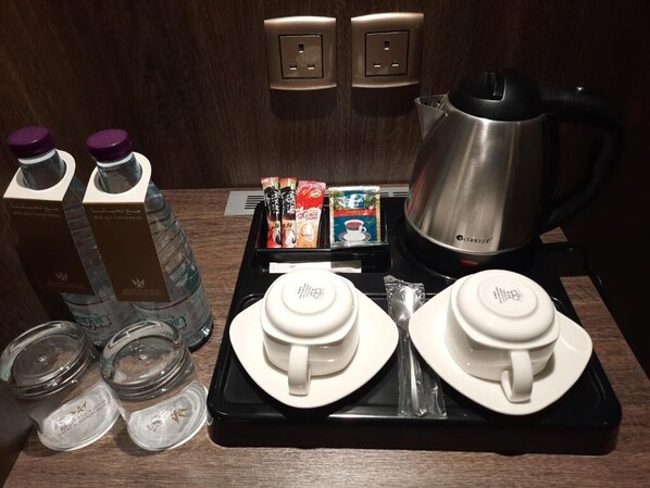 A hotel room's breakfast setup with a coffee maker, tea kettle, and various coffee and tea packets.