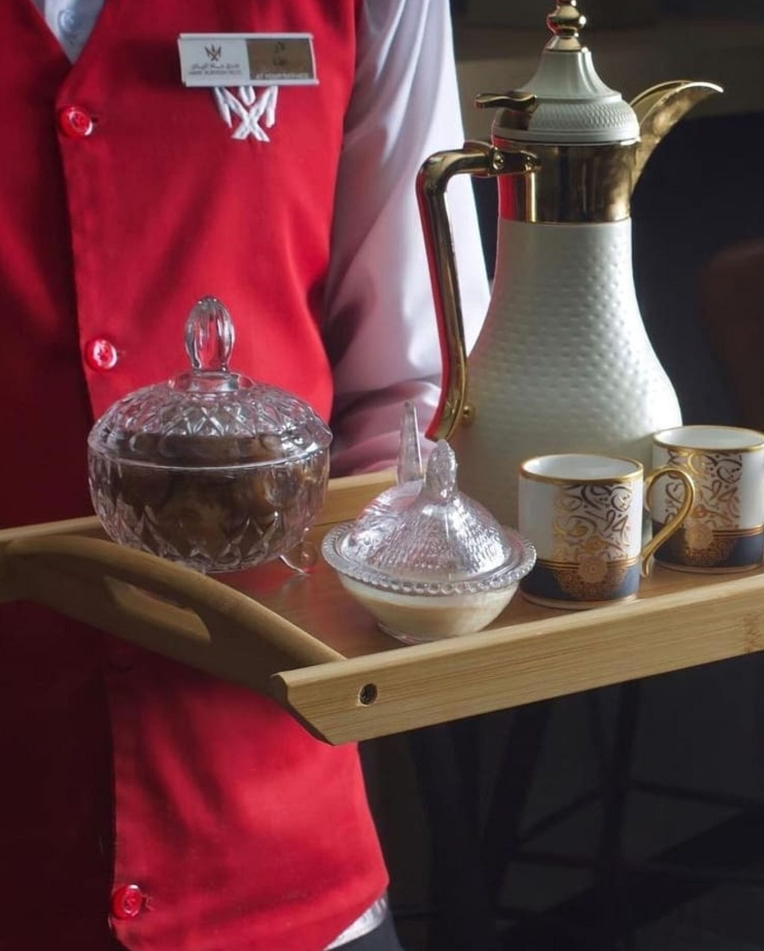 Un plateau sur lequel se trouvent une carafe en cristal, un pichet blanc et deux tasses décorées.