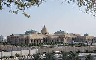 Um edifício grande e histórico, com várias cúpulas e fachada simétrica.