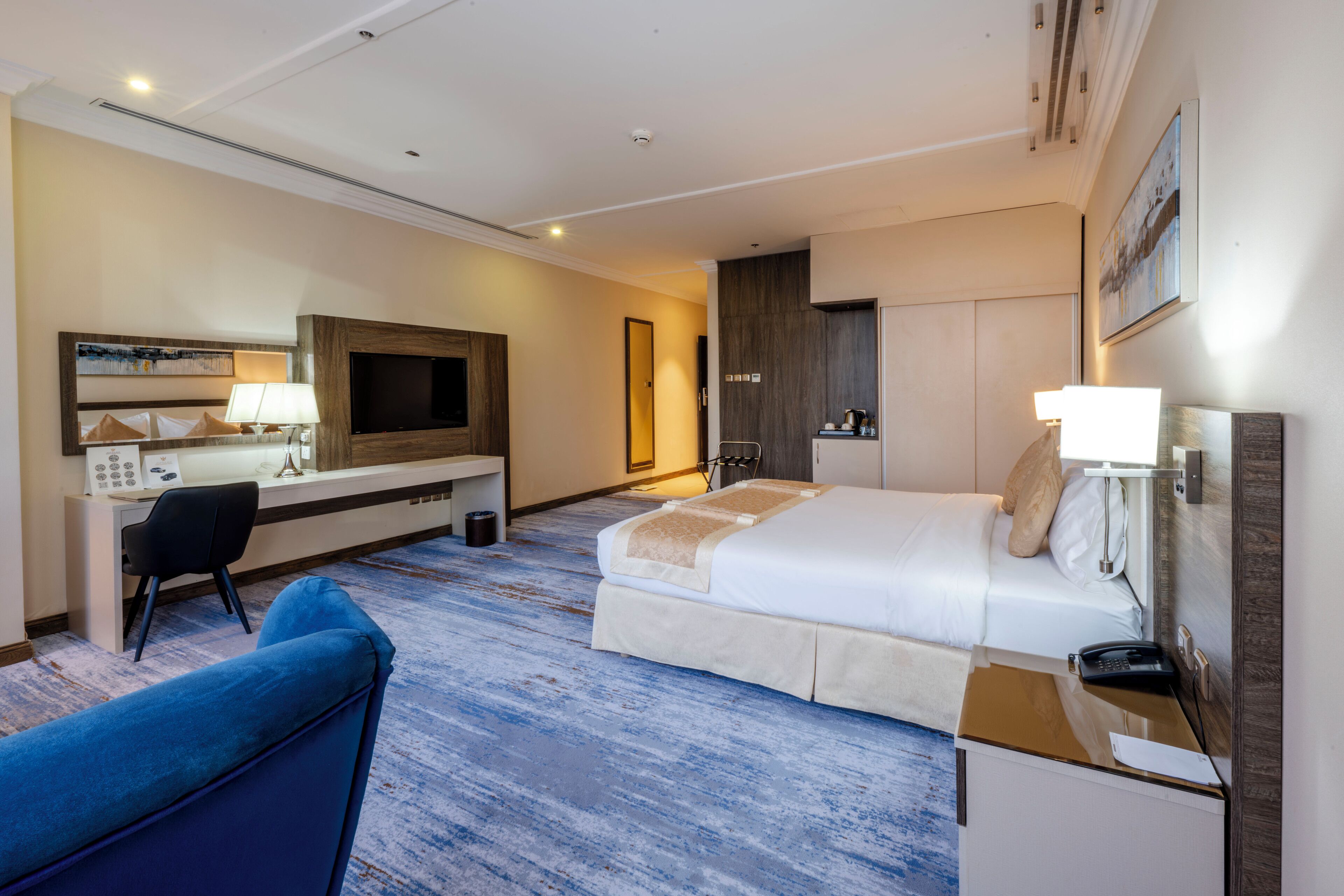 A hotel room with a bed, desk, chair, TV, and a bathroom.