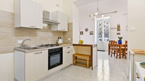 Una cocina moderna con estufa a gas, horno y lavaplatos, un comedor con sillas de madera y una pequeña mesa de madera.