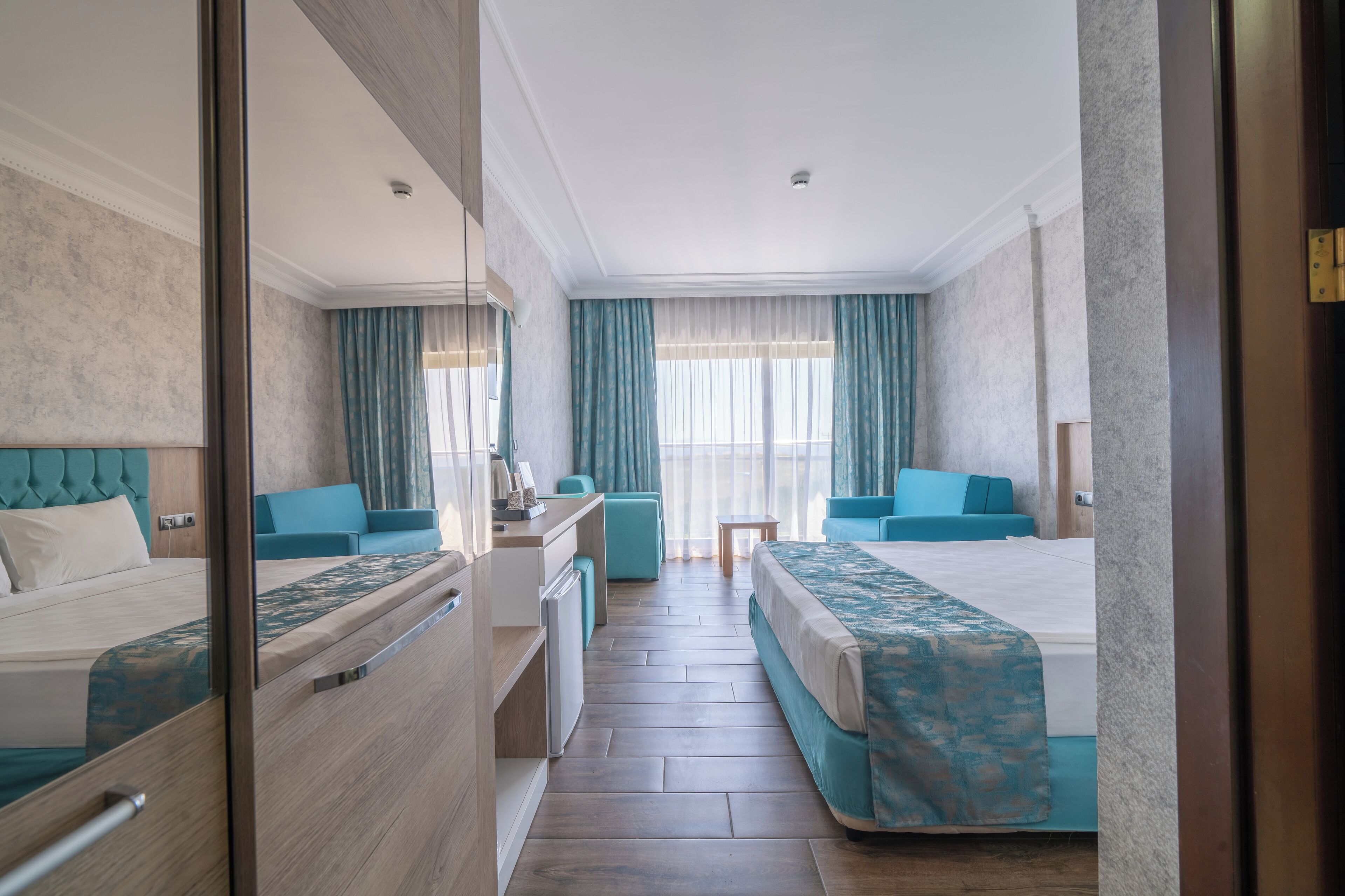 A hotel room with a bed, a desk, a chair, and a small table.