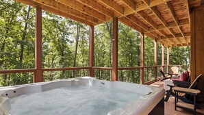 A hot tub on a wooden deck with a view of a forest. - Luxury 4 Bedroom with King Bedroom Suites, Hot Tub, Theater, WiFi, Game Room! (Sevierville)
