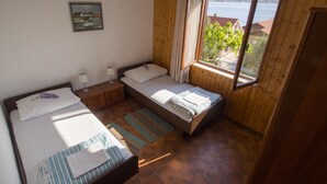Een kamer met twee bedden, een raam met uitzicht op zee en een schilderij aan de muur.