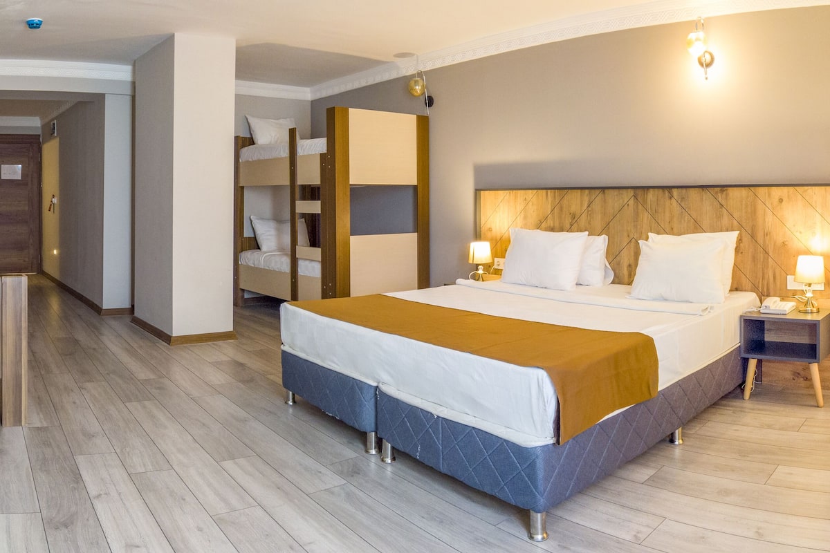 A hotel room with a bed, bedside table, lamp, and a TV mounted on the wall.