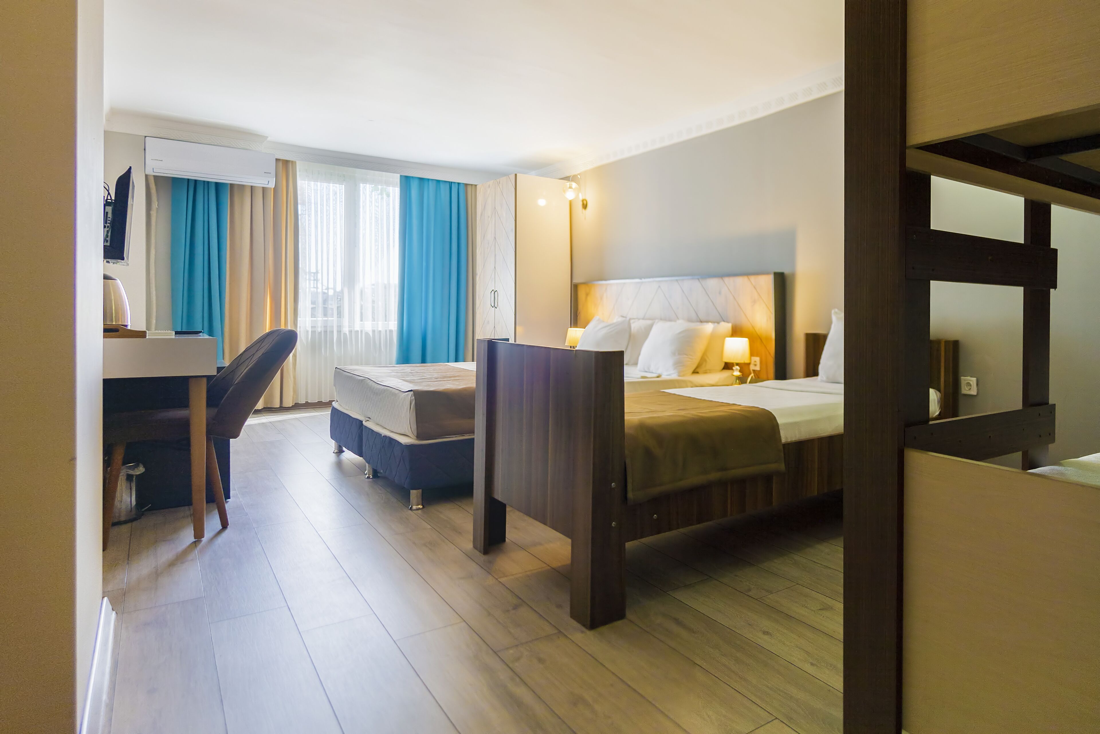 A hotel room with a bed, a desk, a chair, and a window with curtains.