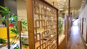 Un pasillo de hotel con un separador de madera, un área de descanso y una escalera que conduce a un nivel superior.