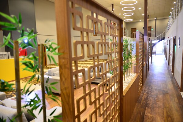 A hotel corridor with a wooden partition, seating area, and a staircase leading to an upper level. - Privado Hotels (Antalya)