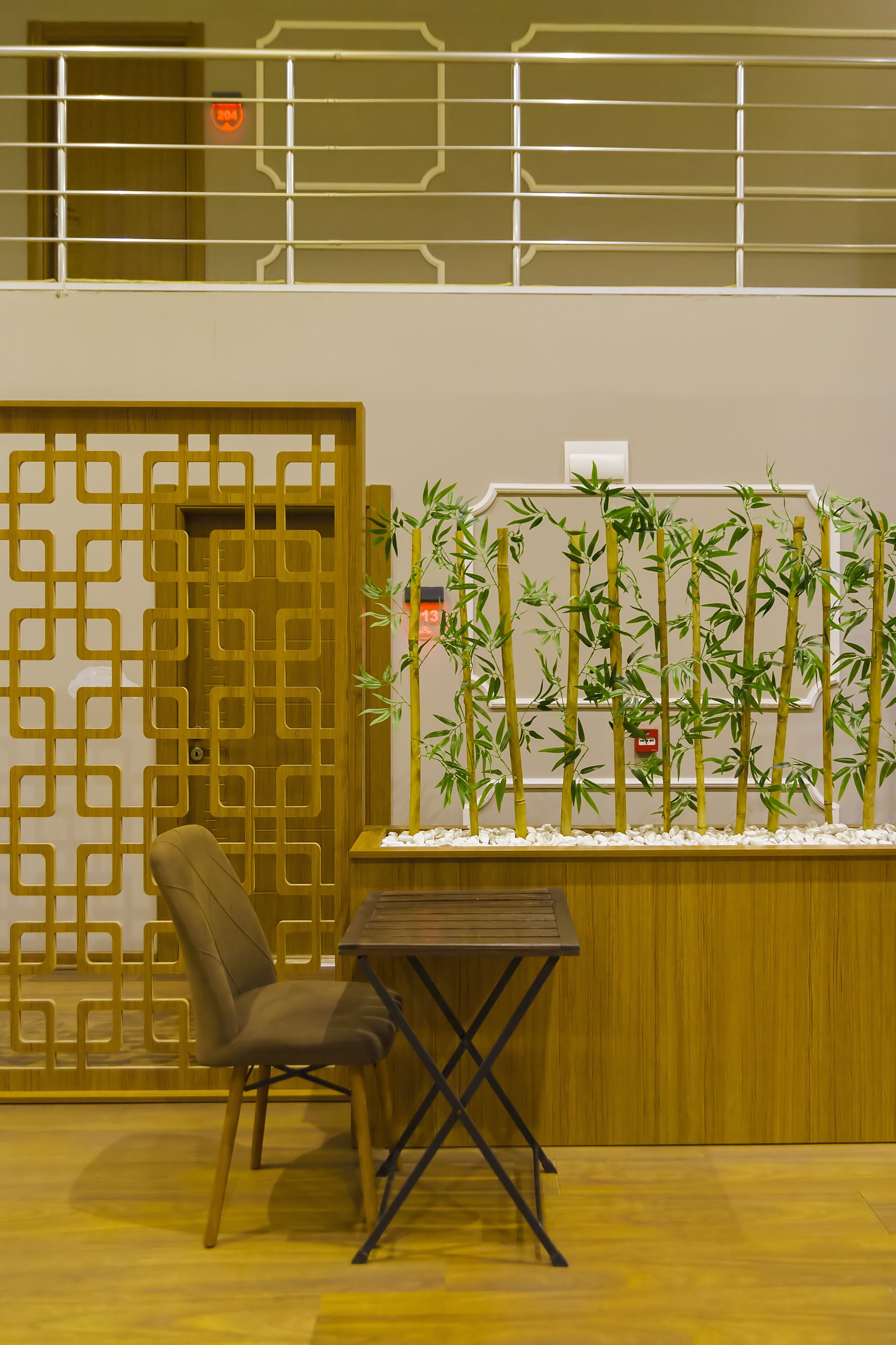 Une pièce comprenant un bureau en bois, une chaise, une plante décorative en bambou et un paravent traditionnel en bois.