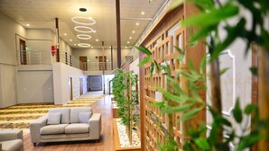 Un vestíbulo de hotel con un sofá, piso de madera y una planta.