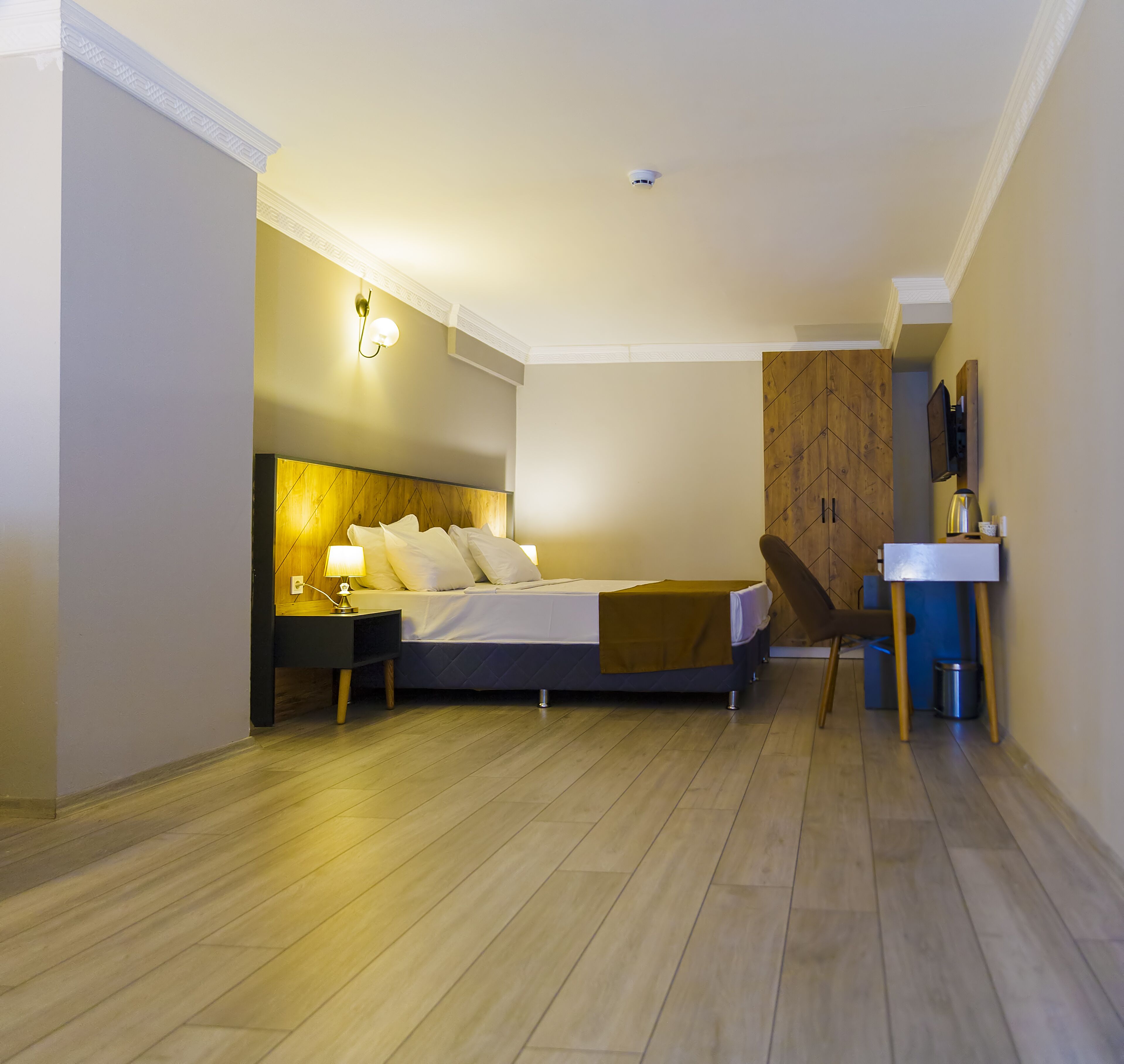 Un dormitorio moderno con cama, mesita de noche, lámpara y un armario de madera.