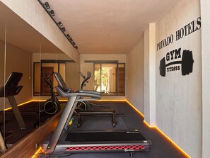 Un gimnasio con cintas de correr, bicicletas estáticas y un espejo grande.
